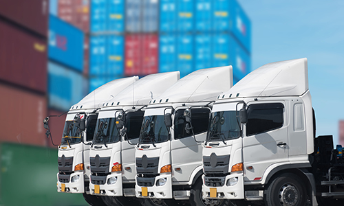 A lineup of trucks parked closely together in a parking area, showcasing various colors and sizes.